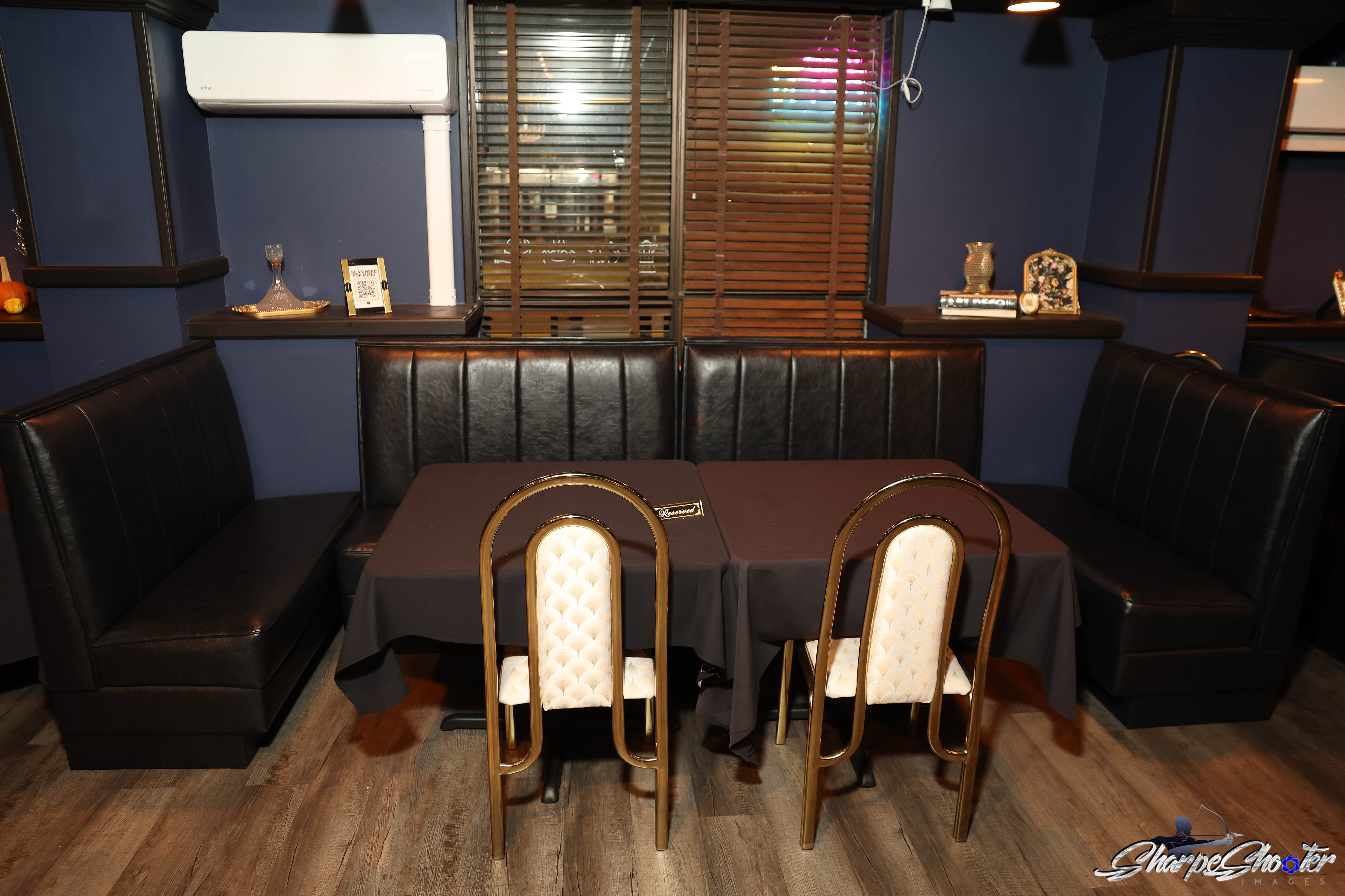 Black leather booth seating with gold arched chairs at a reserved table